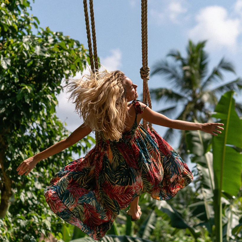 A woman in a tropical-print dress on a jungle swing in Bali