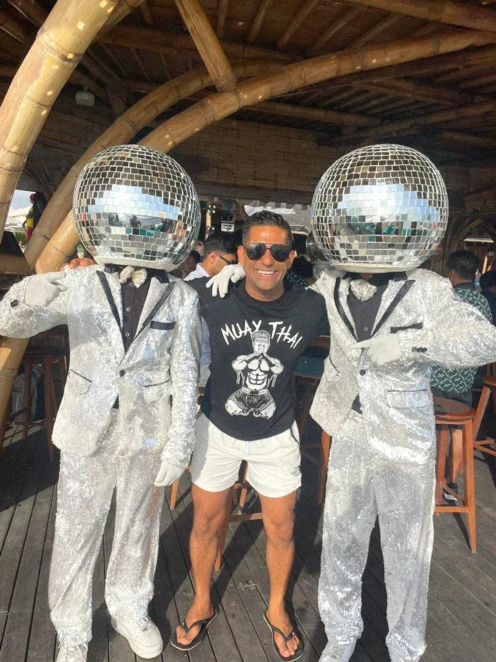 Randy at a beach club between two mirror-ball performers
